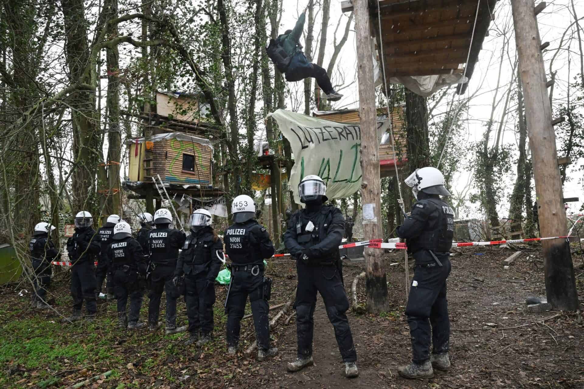 Polițiștii stau în fața colibelor construite în copaci de activiștili de mediu, în timpul celei de-a treia zile de evacuare a cătunului de lignit Luetzerath, ocupat de activiștii pentru mediu. Foto: Federico Gambarini/dpa