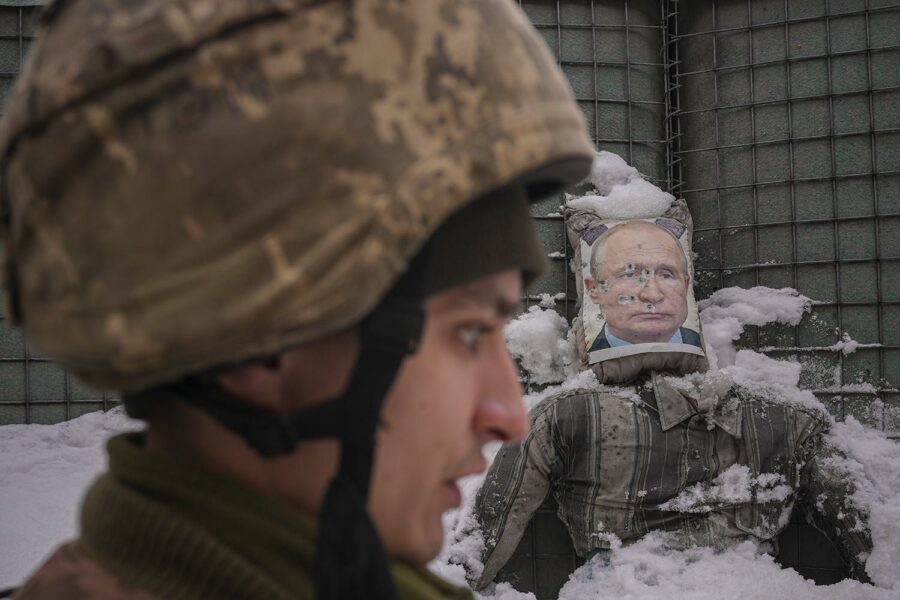 Un militar ucrainean vorbește, având în spate o efigie ciuruită de gloanțe a președintelui rus Vladimir Putin, în timpul unui interviu pentru presă pe frontul din Luhansk, în estul Ucrainei, pe 1 februarie 2022. (AP Photo/Vadim Ghirda)
