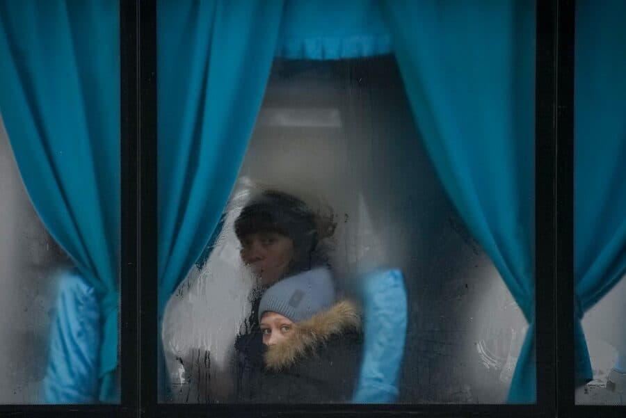 O femeie și un copil se uită pe fereastra unui autobuz, în timp ce părăsesc Sievierodonetsk, regiunea Luhansk, în estul Ucrainei, pe 24 februarie 2022. (AP Photo/Vadim Ghirda)