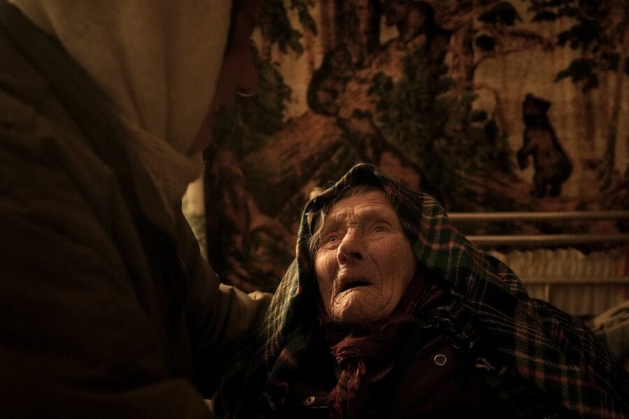 Motria Oleksiienko, în vârstă de 99 de ani, traumatizată de ocupația rusă, este consolată de Tetiana Oleksiienko într-o cameră fără încălzire din satul Andriivka, Ucraina, puternic afectat de luptele dintre forțele ruse și ucrainene, miercuri, 6 aprilie 2022. Mai multe clădiri din sat au fost reduse la mormane de cărămizi și metal ondulat, iar locuitorii se luptă fără căldură, electricitate sau gaz de gătit. (AP Photo/Vadim Ghirda)